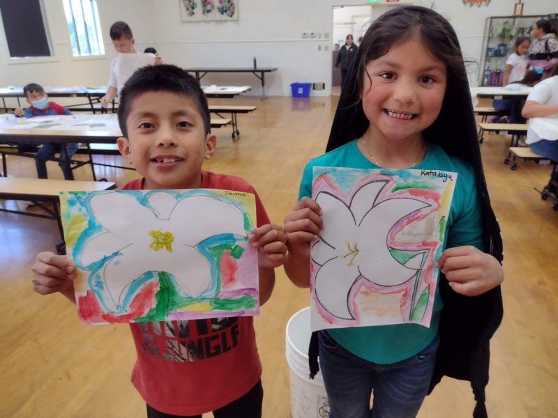 students holding watercolor portraits